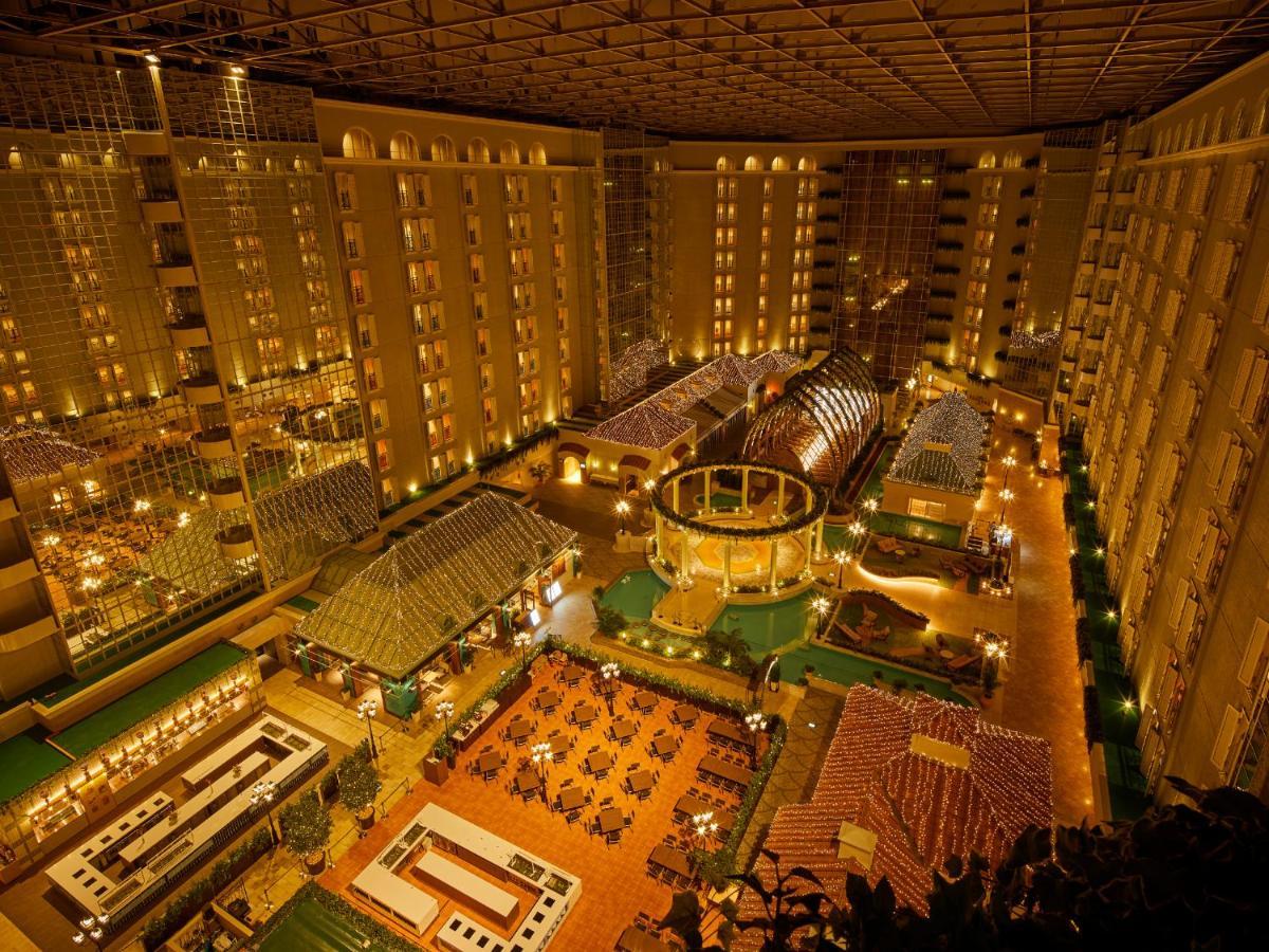 Grand Nikko Tokyo Bay Maihama Otel Urayasu Dış mekan fotoğraf The photo shows a large, illuminated atrium of a hotel or resort complex. Several floors of what appear to be guest rooms or apartments surround the central area. The atrium contains a variety of amenities, including a pool or water feature, landscap
