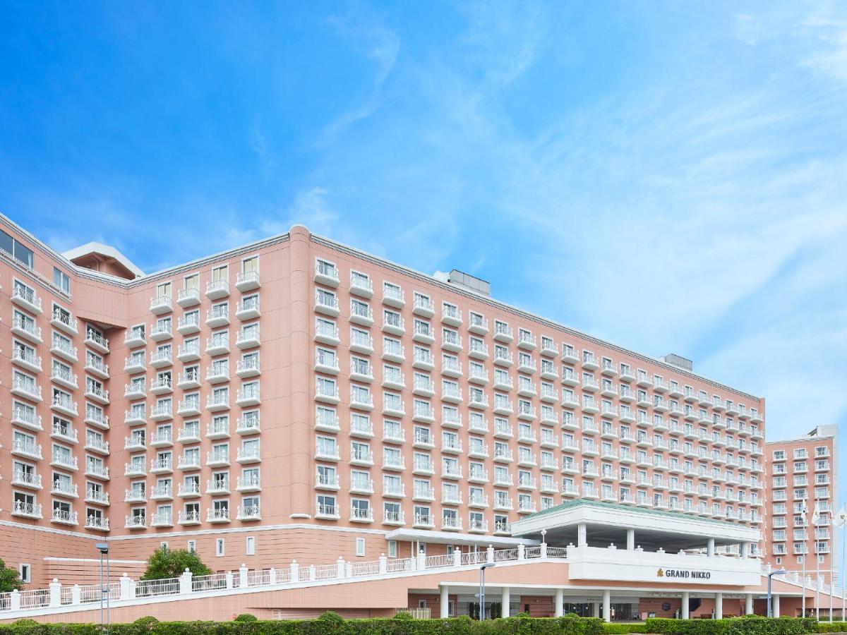Grand Nikko Tokyo Bay Maihama Otel Urayasu Dış mekan fotoğraf The photo depicts a large hotel building featuring a contemporary architectural design. The structure is predominantly pink, with multiple floors and numerous windows. There is a covered entrance at the front, and the setting appears to be well-maint
