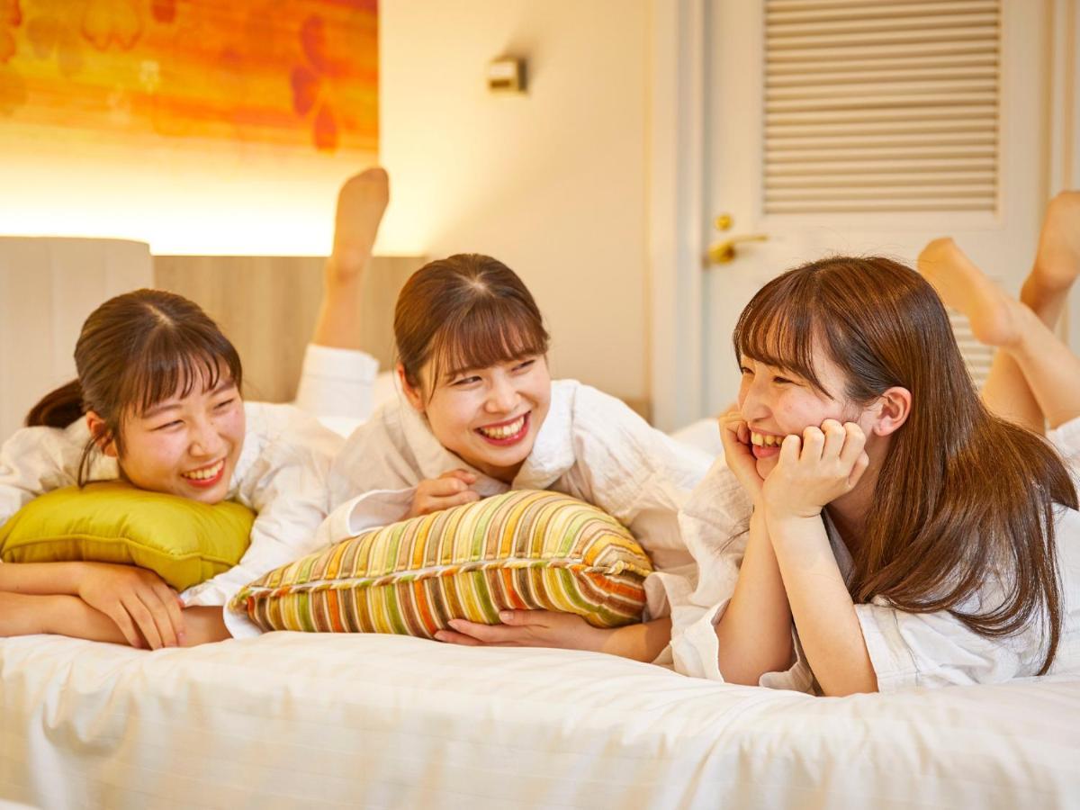Grand Nikko Tokyo Bay Maihama Otel Urayasu Dış mekan fotoğraf The photo shows three young women lounging together in a cozy indoor setting. They are dressed in white robes and appear to be relaxed and enjoying each other's company. The women are lying on a bed, with two of them resting on their arms and the thi