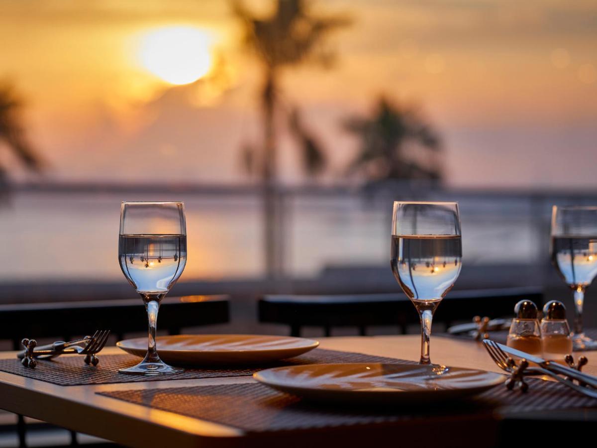 Grand Nikko Tokyo Bay Maihama Otel Urayasu Dış mekan fotoğraf The photo depicts a picturesque dining setting at sunset. In the foreground, there are two elegantly arranged tables, each set with plates and glasses filled with water. The glasses are crystal clear, reflecting the warm colors of the sunset. Behind 