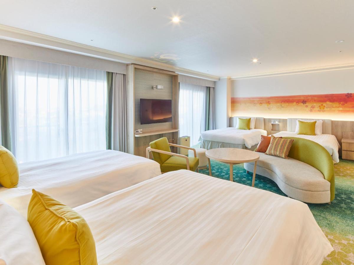 Grand Nikko Tokyo Bay Maihama Otel Urayasu Dış mekan fotoğraf The photo shows a modern hotel room that features two large beds covered with white bedding and decorative pillows. There is a contemporary, curved sofa in a light color, along with a round table in the middle. The room has large windows that allow n