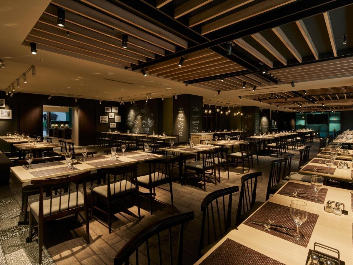 Grand Nikko Tokyo Bay Maihama Otel Urayasu Dış mekan fotoğraf The photo shows the interior of a modern restaurant. The space features a spacious dining area with several long tables arranged in rows. Each table is set with dining utensils, plates, and glasses, indicating readiness for patrons. The lighting is s