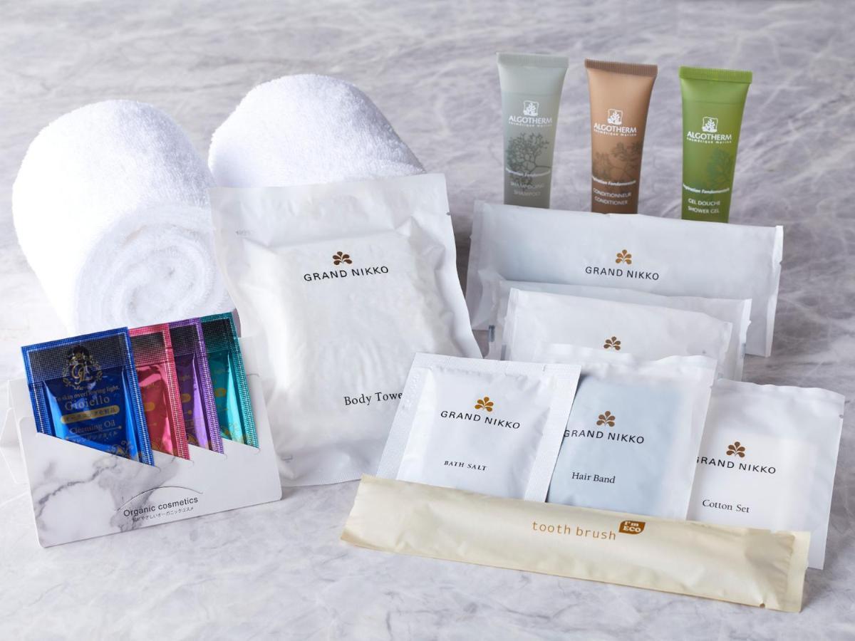 Grand Nikko Tokyo Bay Maihama Otel Urayasu Dış mekan fotoğraf The photo displays a collection of spa or hotel toiletries. It includes:

- Two fluffy white towels.
- Multiple packages labeled "GRAND NAKO," which appear to be spa or body care products.
- Several small tubes of hair and body care items in green an