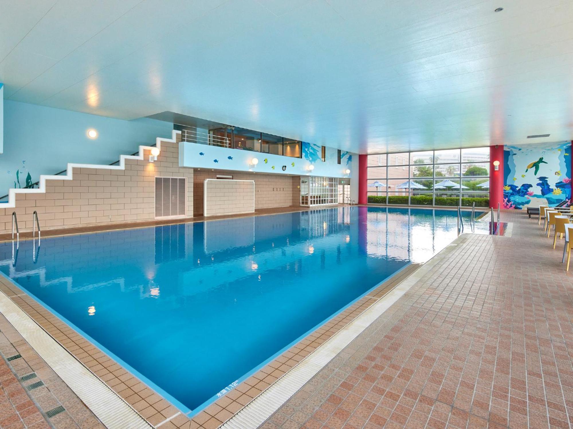 Grand Nikko Tokyo Bay Maihama Otel Urayasu Dış mekan fotoğraf The photo shows an indoor swimming pool area with a spacious design. The pool has a clear blue water surface and is surrounded by a tiled deck. On one side of the pool, there are steps leading into the water, and there are large windows letting in na