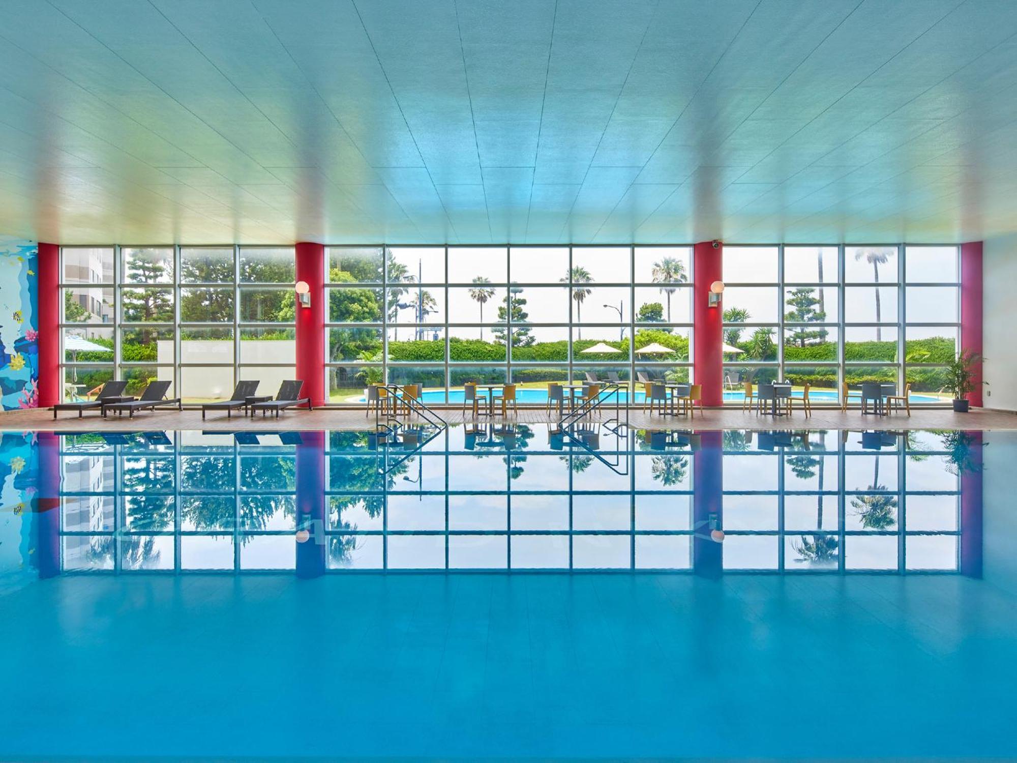 Grand Nikko Tokyo Bay Maihama Otel Urayasu Dış mekan fotoğraf The photo shows an indoor swimming pool with bright blue water. The pool area is spacious, characterized by large windows that allow natural light to flood in, creating a vibrant atmosphere. The walls are painted in a soft color, with accents of red.