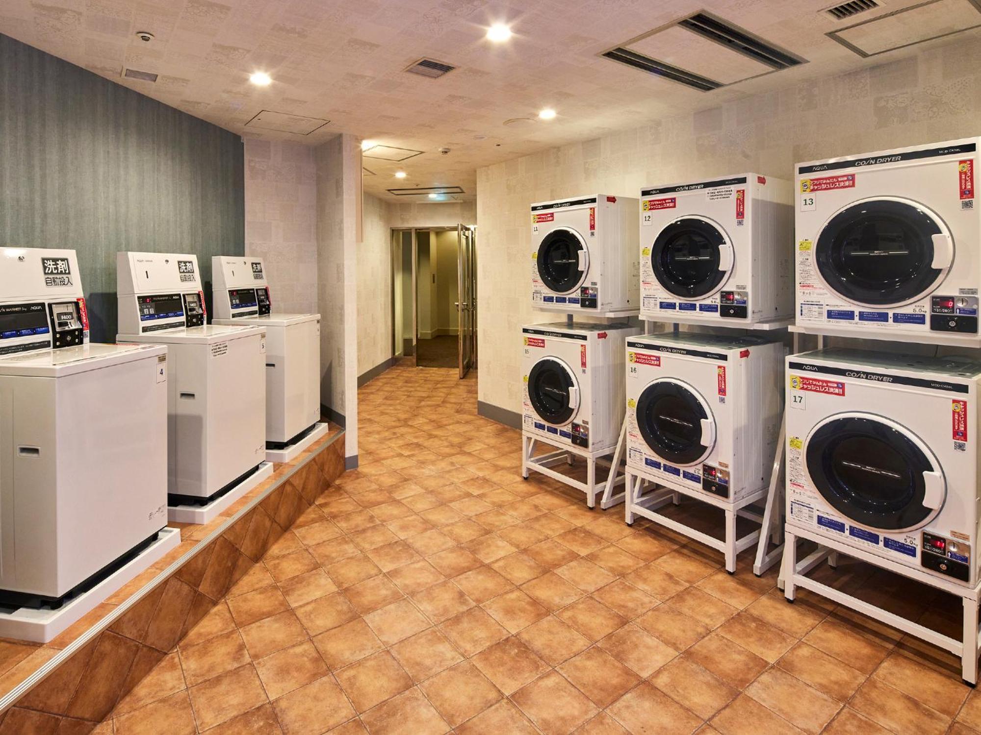 Grand Nikko Tokyo Bay Maihama Otel Urayasu Dış mekan fotoğraf The photo shows a laundry room with several washing machines and dryers. On the left side, there are five white washing machines, and on the right side, there are four dryers. The machines are arranged in a clean, tiled space with a neutral-colored w