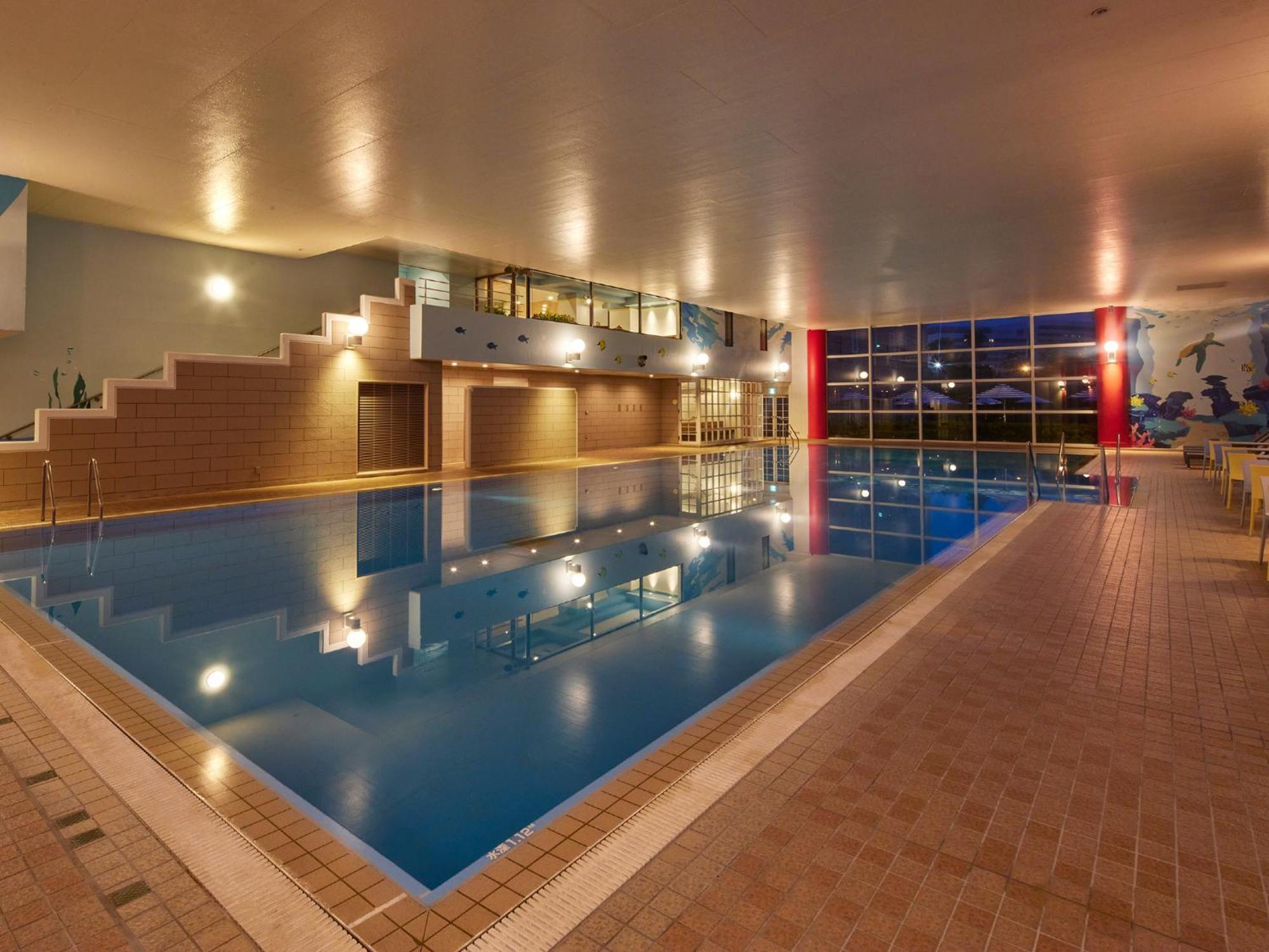 Grand Nikko Tokyo Bay Maihama Otel Urayasu Dış mekan fotoğraf The photo shows an indoor swimming pool area. The pool features a calm blue water surface and is surrounded by tiled flooring. There is a staircase leading to a higher level, likely providing access to a lounge or seating area. Large windows allow na